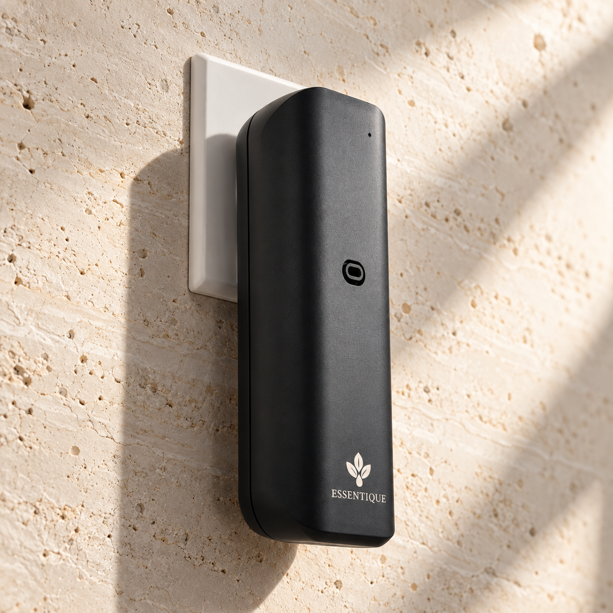 Three-quarter side view of the black Pulse diffuser plugged into a wall outlet on a pale stone wall.